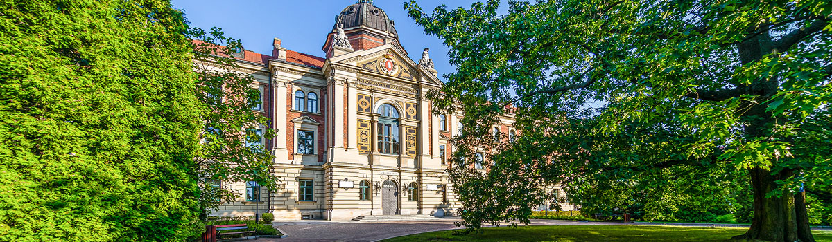 Zdjęcie frontowe, budynek Główny UEK w otoczeniu drzew